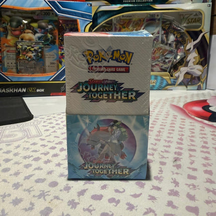 Pokémon trading card game box with 'Journey Together' on a patterned surface